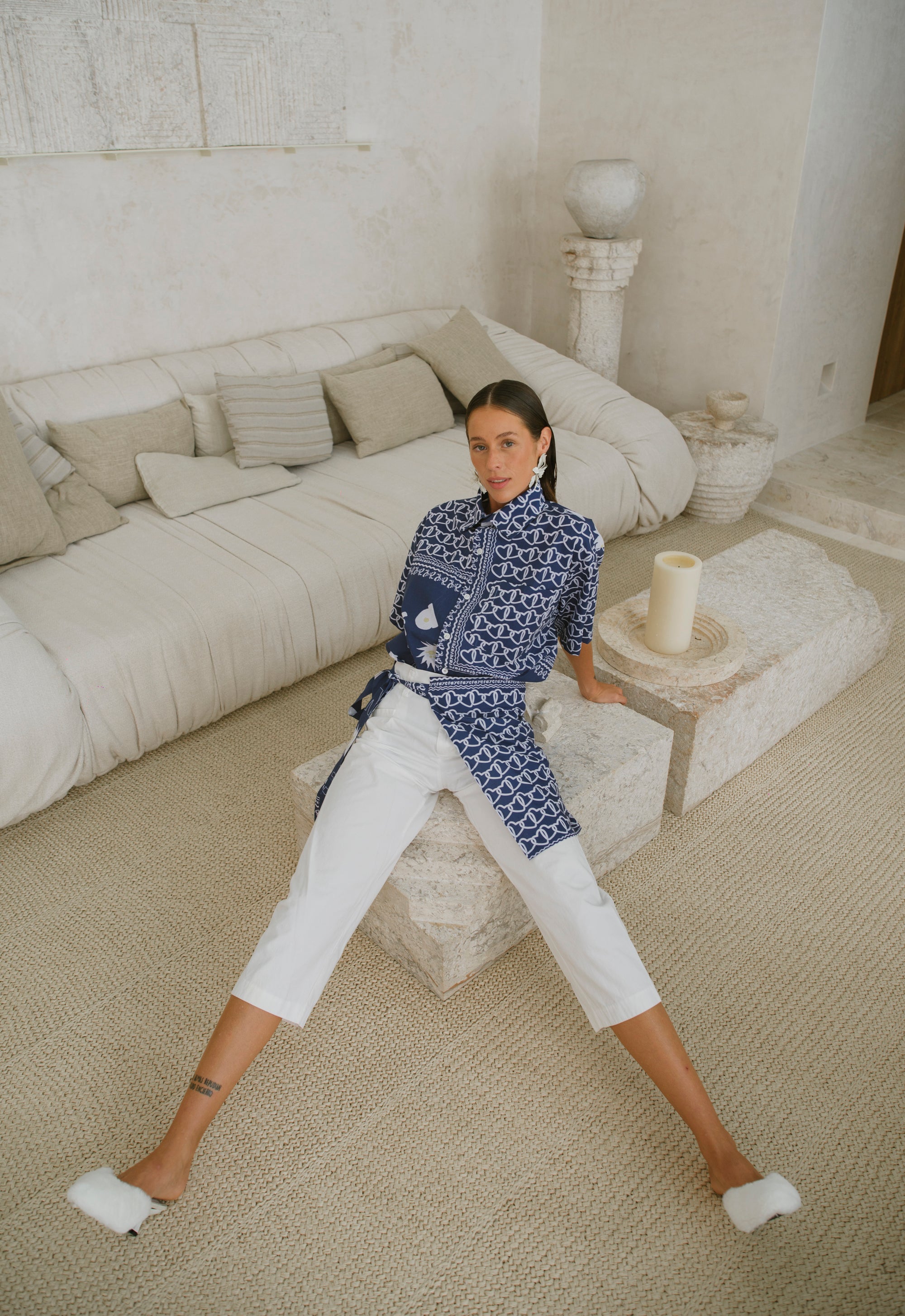 Woman sitting on a stone stool in a modern living room.