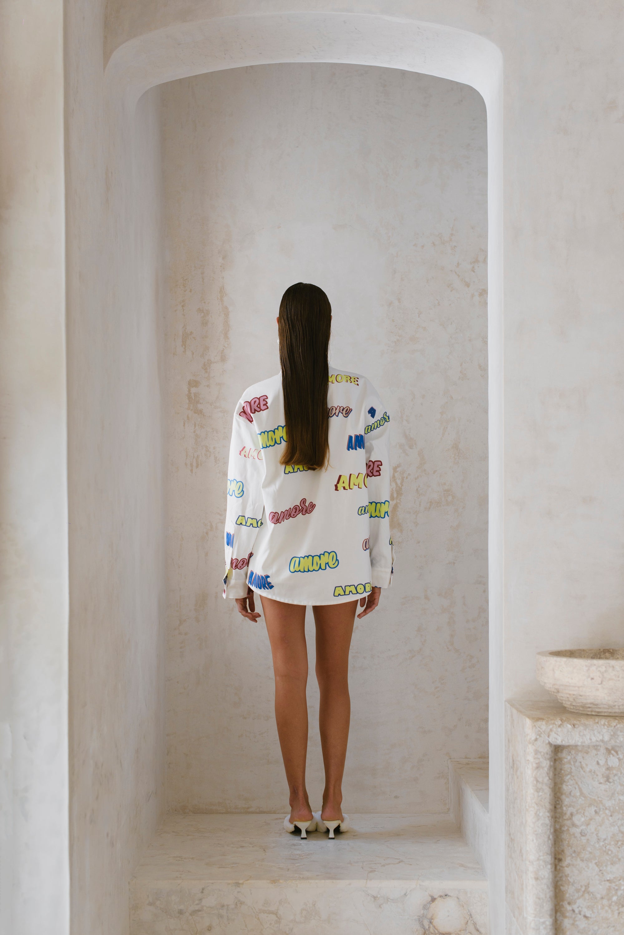 Woman wearing a colorful oversize standing in a marble hallway