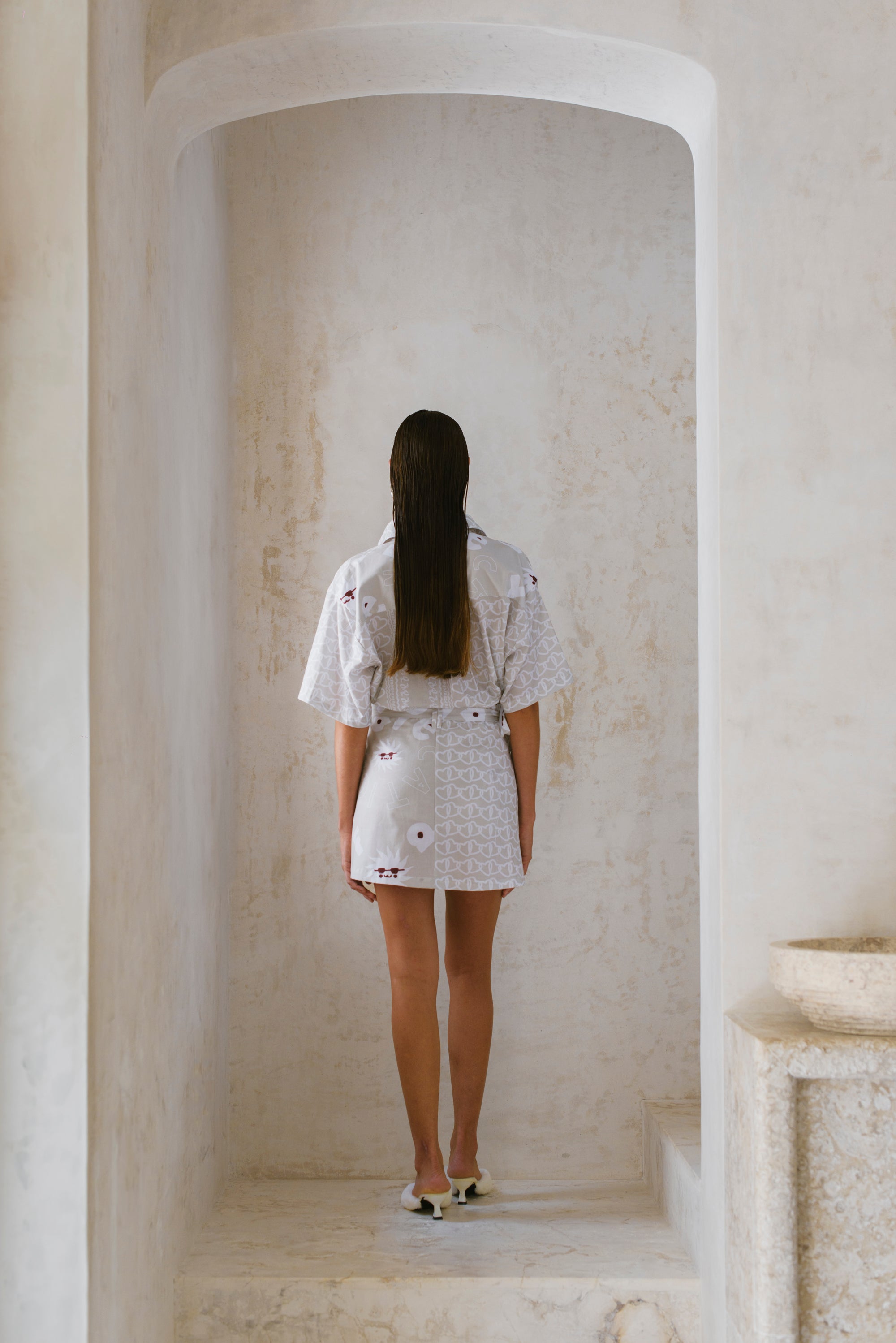 Woman in a white skirt standing in a marble hallway