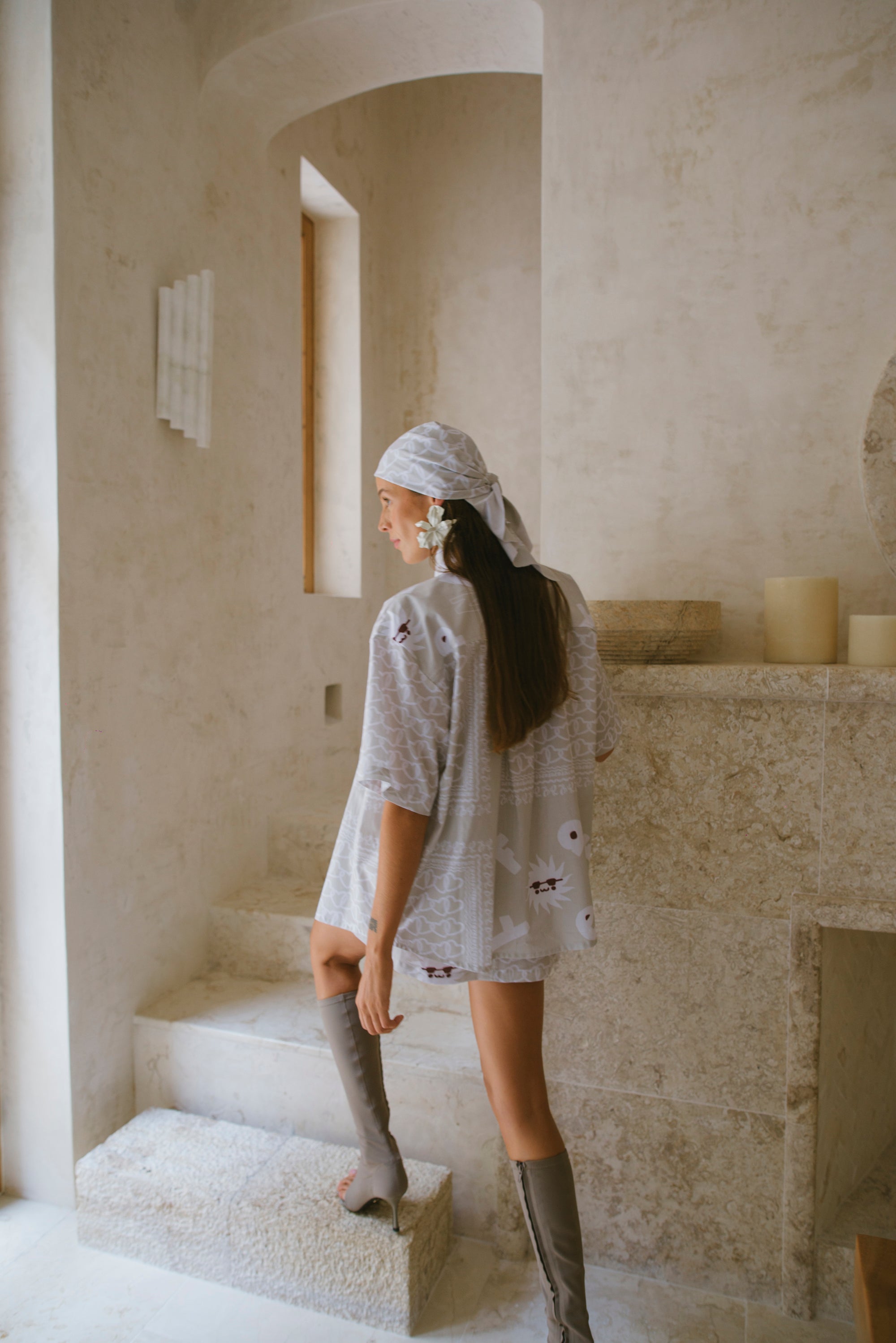 Woman in a beige patterned outfit standing in a marble room