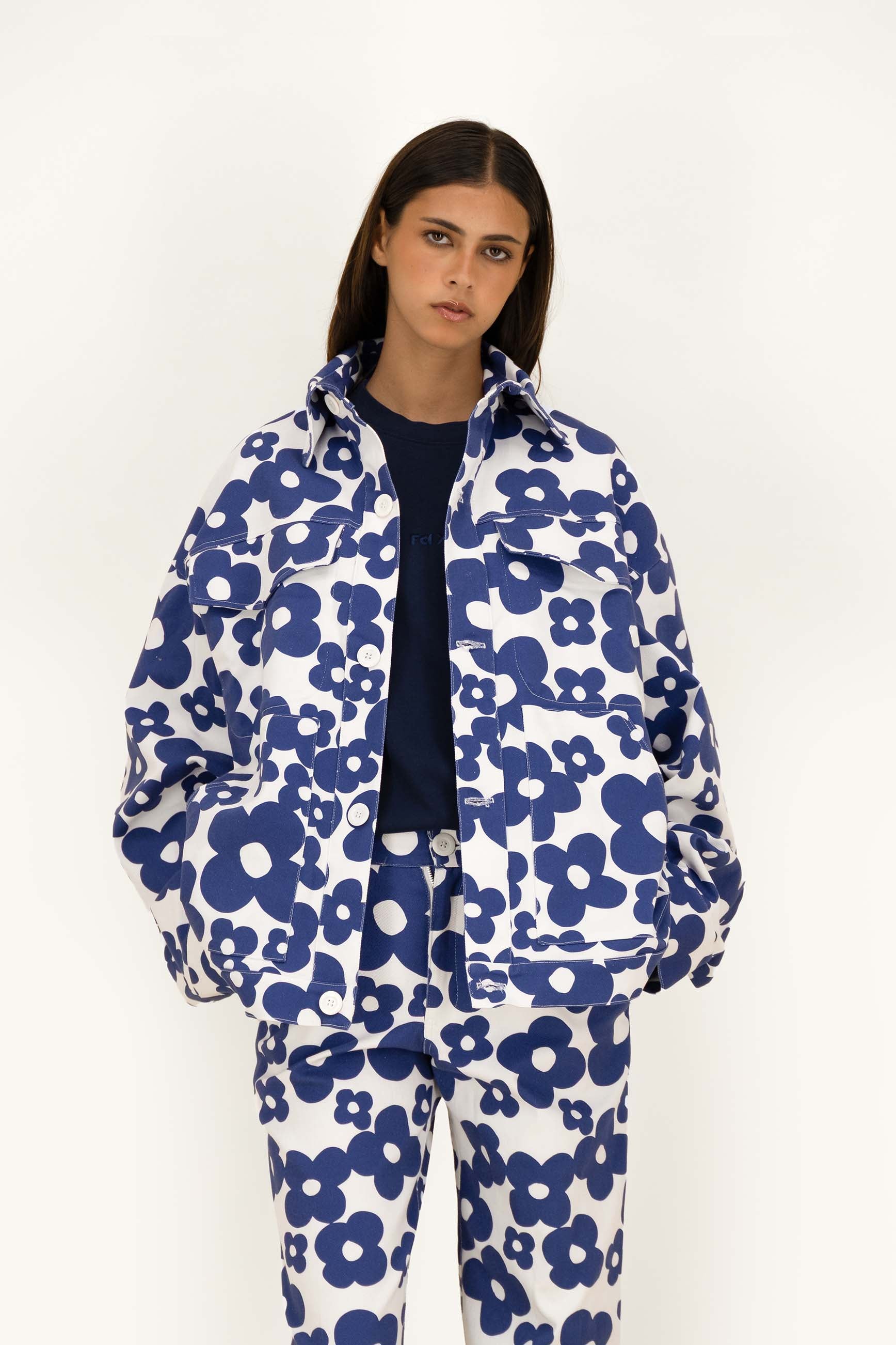 A model wearing a matching navy blue and white floral print vest and pants set, styled over a dark navy crewneck shirt, against a plain white studio background.