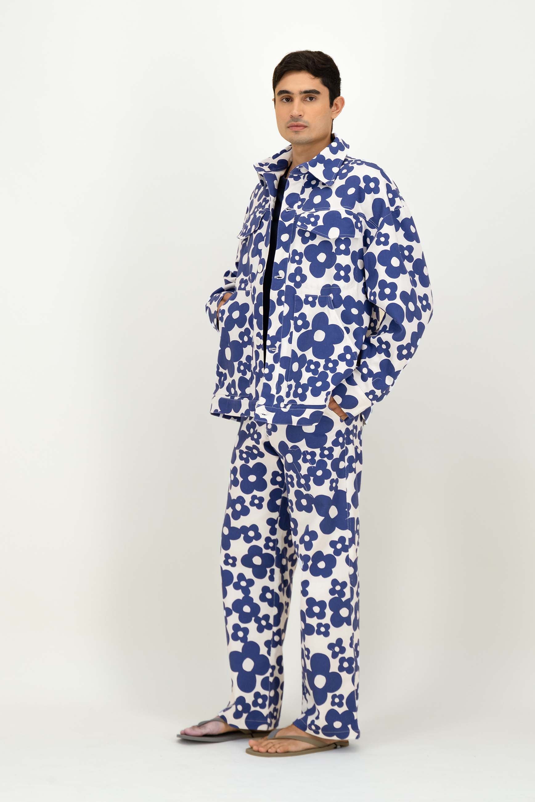 A man modeling a matching two-piece set with a bold blue and white floral pattern, standing against a plain light gray studio background.