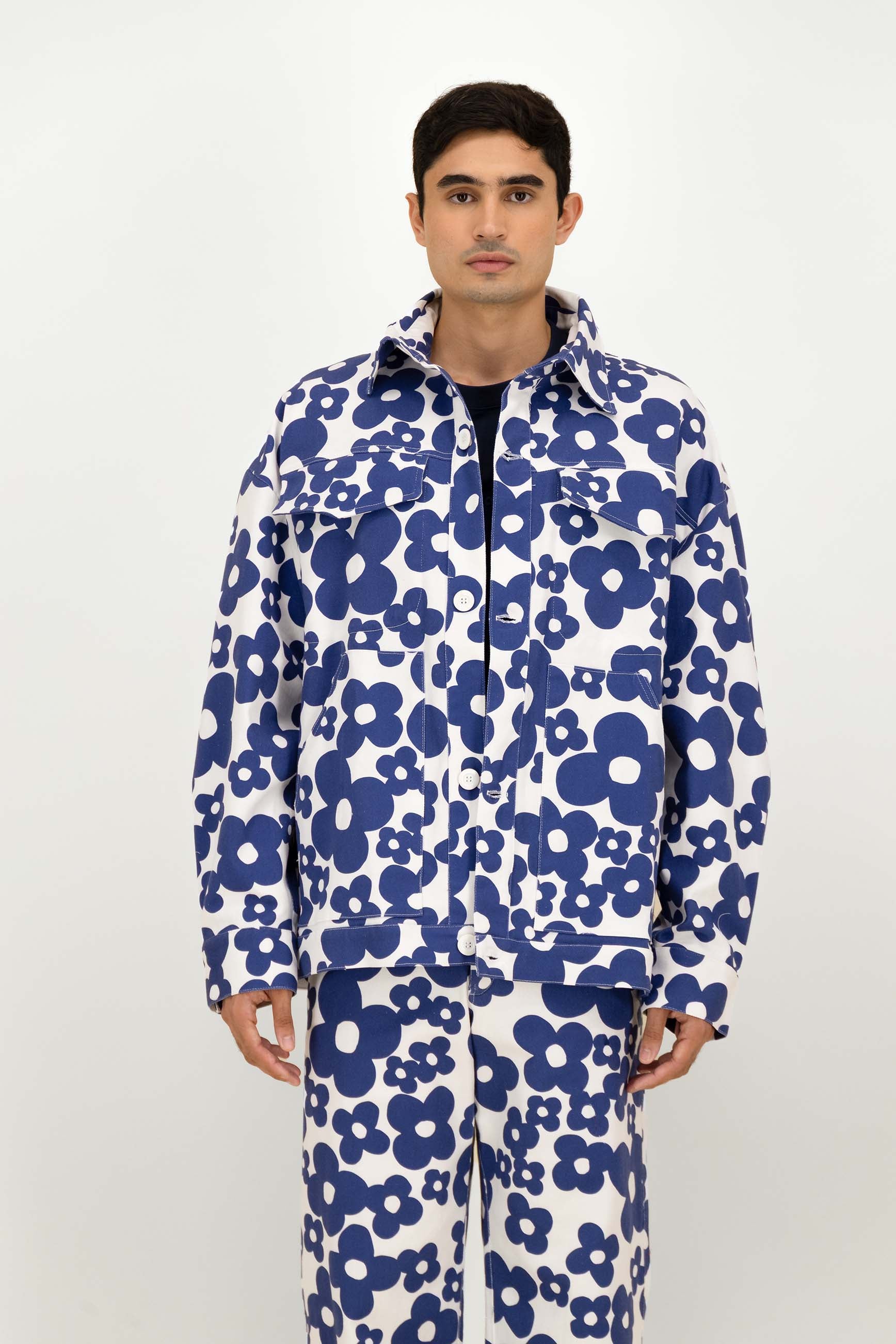 A man wearing a matching two-piece with a bold blue and white floral pattern, standing against a plain light gray studio background.