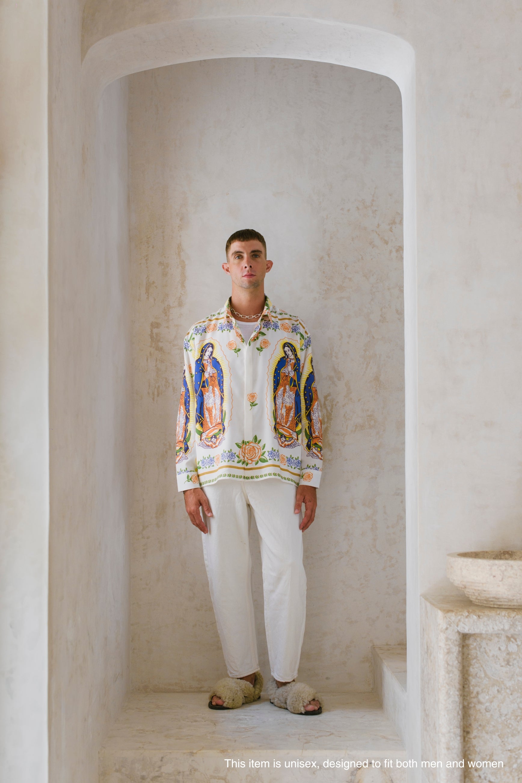 Man wearing a colorful shirt with the virgin de guadalupe iconography in a marble hallway.